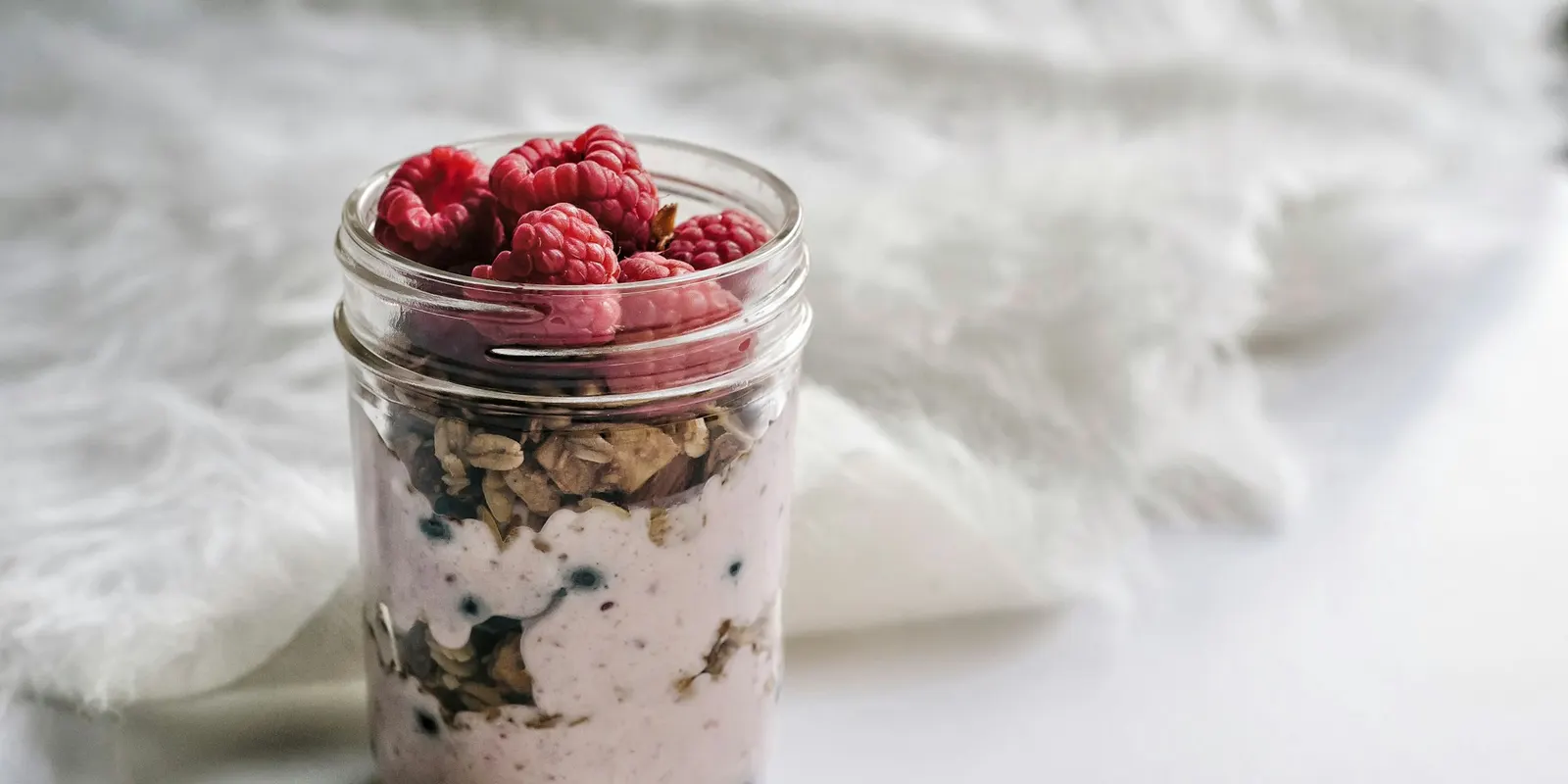 A jar of overnight oats topped with raspberries