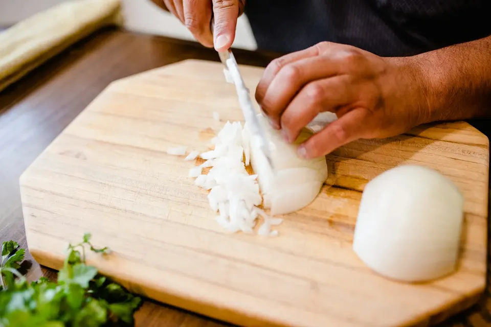 Dicing an onion on a wooden chopping board